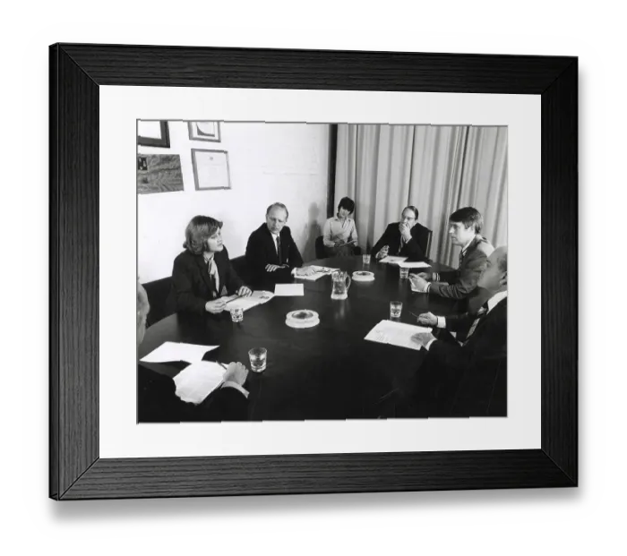 Framed Print : A group of men and women sit around a table holding a board meeting. A (female) secretary takes notes. Date: circa 1970 Framed Print : A group of men and women sit around a table holding a board meeting. A (female) secretary takes notes. Date: circa 1970
