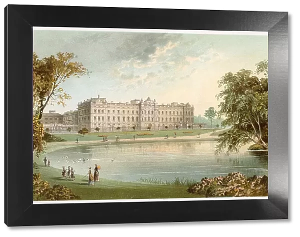 A view of Buckingham Palace across the lake in St James Park. Elegant woman and children stroll around the edge of the lake. Date: circa 1890