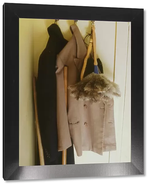 Two overcoats and a feather duster, hanging from three hooks behind a bedroom door. Date: 1940s (re-enactment)