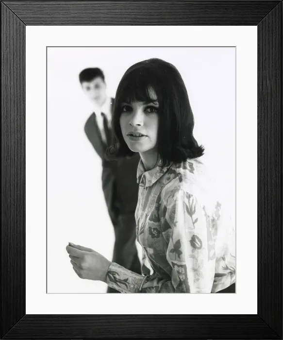 Framed Print : A young woman poses in the foreground with an out of focus male standing behind. Date: mid 1960s Framed Print : A young woman poses in the foreground with an out of focus male standing behind. Date: mid 1960s