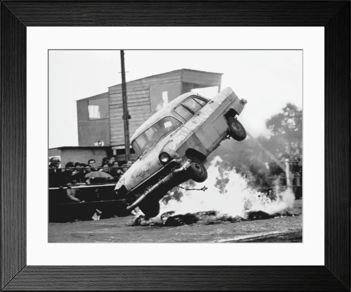 Framed Print : A stunt car flies through the air over a bonfire of tyres, watched by spectators standing in the rain. Date: 1960s Framed Print : A stunt car flies through the air over a bonfire of tyres, watched by spectators standing in the rain. Date: 1960s
