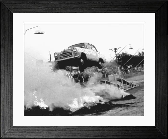 Framed Print : A stunt car flies through the air over a bonfire of tyres, watched by spectators standing in the rain. Date: 1960s Framed Print : A stunt car flies through the air over a bonfire of tyres, watched by spectators standing in the rain. Date: 1960s