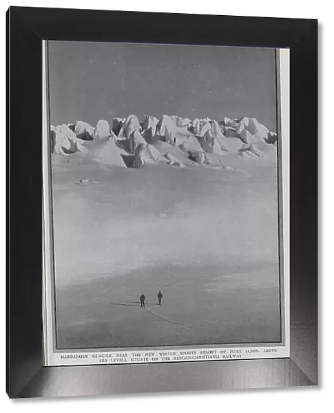 Photograph of the Hardanger Glacier, with two men on skis viewing the scene. Captioned, A Chain of Ice-Hills: A Future Haunt of the Winter Sports Enthusiast