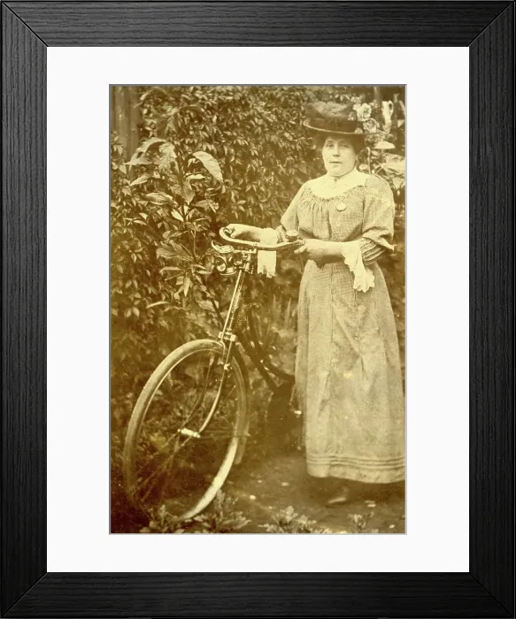 Framed Print : Woman standing in a garden with her bicycle