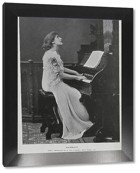 Woman seated at keyboard of a pipe organ, studio portrait