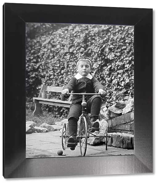 Boy playing on tricycle, early 1900s