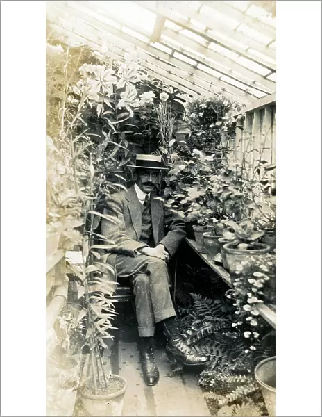 Gentleman Gardener seated proudly in small home greenhouse