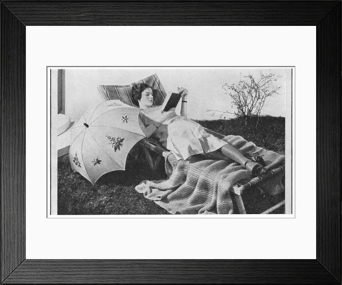 Framed Print : Model reading on a garden lounger with an umbrella, wearing very thick silk stockings, advertising patterns for an embroidered sunshade and knitted blanket. Date: 1935 Framed Print : Model reading on a garden lounger with an umbrella, wearing very thick silk stockings, advertising patterns for an embroidered sunshade and knitted blanket. Date: 1935