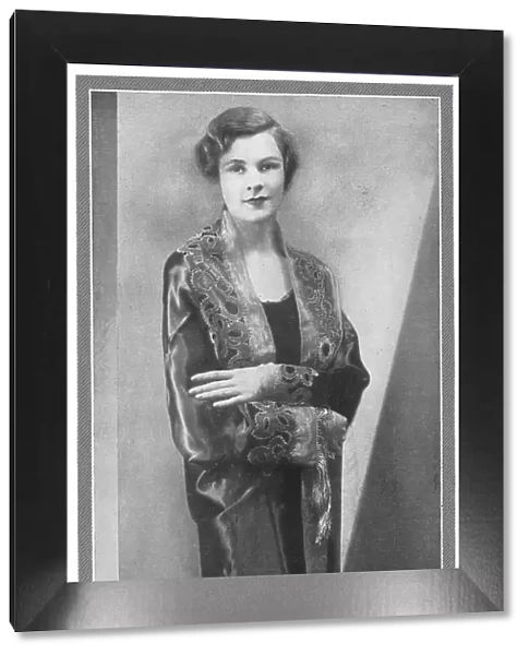 Illustration of a lady wearing an elegant evening coat, with deep embroidery on the collar and cuffs. Date: 1930