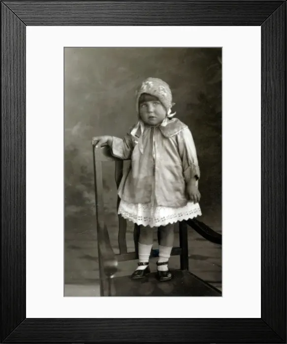 Framed Print : Young girl posing for studio photograph standing on a chair Framed Print : Young girl posing for studio photograph standing on a chair