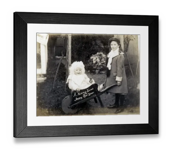 Framed Print : Young girl with her baby sister in a small wheelbarrow - A Merry Christmas card. Date: circa 1908 Framed Print : Young girl with her baby sister in a small wheelbarrow - A Merry Christmas card. Date: circa 1908