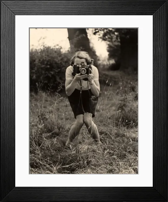 Framed Print : Smile. A woman with a camera adopts a photographers pose for - another photographer Framed Print : Smile. A woman with a camera adopts a photographers pose for - another photographer