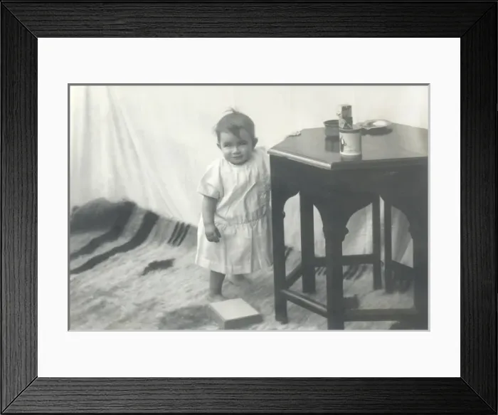 Framed Print : Smiling toddler leaning against a table Framed Print : Smiling toddler leaning against a table