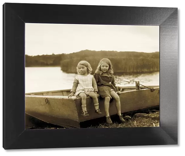 Two little girls sitting on the edge of a boat, Scotland