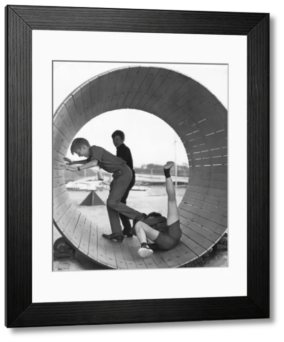 Framed Print : Three boys playing inside a large barrel Framed Print : Three boys playing inside a large barrel