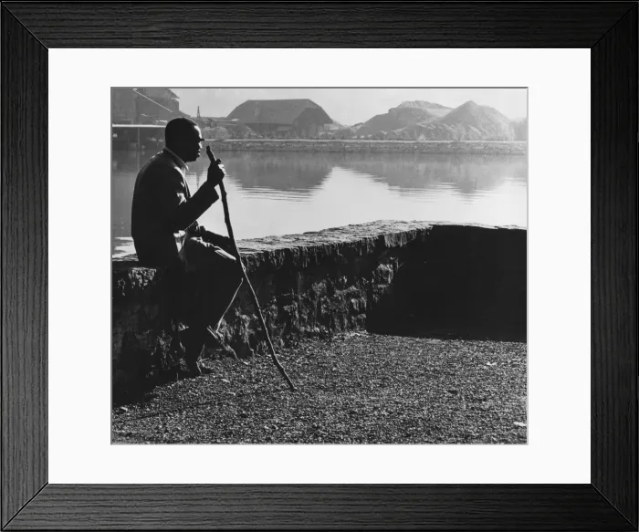 Framed Print : Man sitting on a wall by a stretch of water Framed Print : Man sitting on a wall by a stretch of water