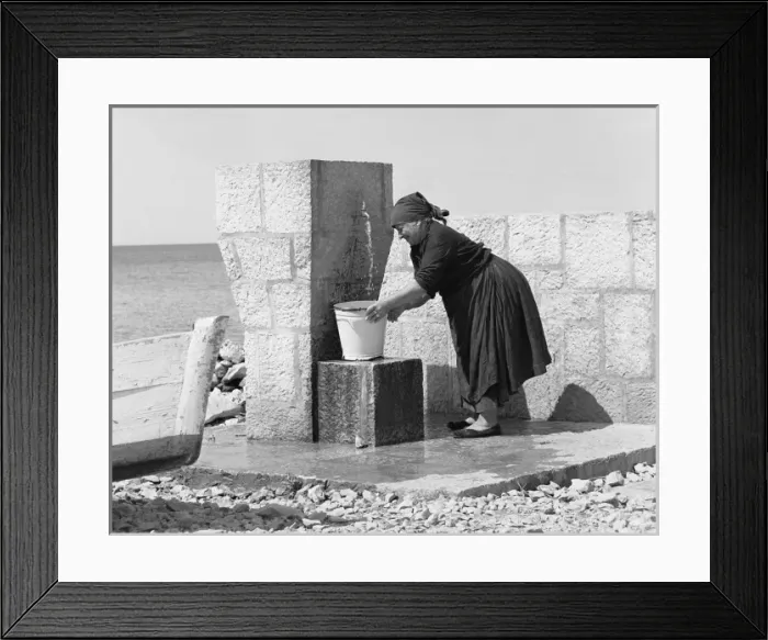 Framed Print : Woman filling a bucket from an outdoor tap Framed Print : Woman filling a bucket from an outdoor tap