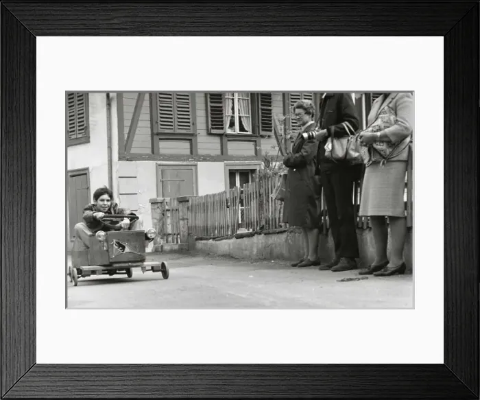 Framed Print : Boy on a go-kart passing three adults Framed Print : Boy on a go-kart passing three adults
