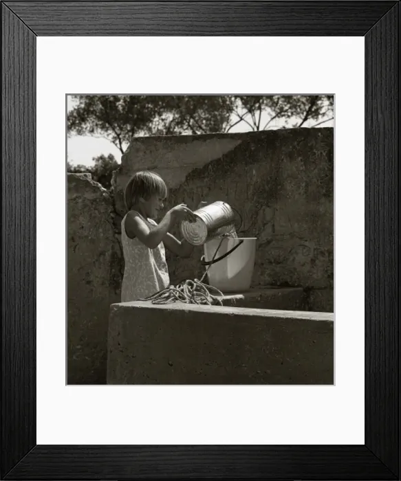 Framed Print : Girl pouring water from a tin into a bucket Framed Print : Girl pouring water from a tin into a bucket