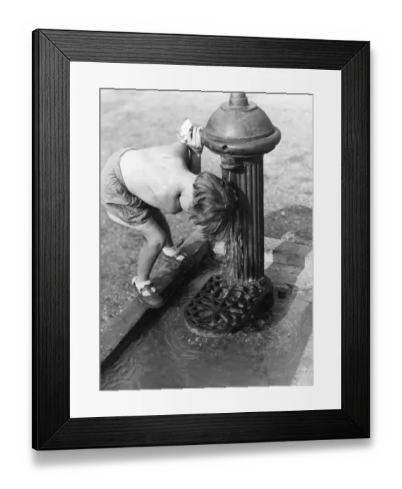 Framed Print : Young child with head under hydrant Framed Print : Young child with head under hydrant