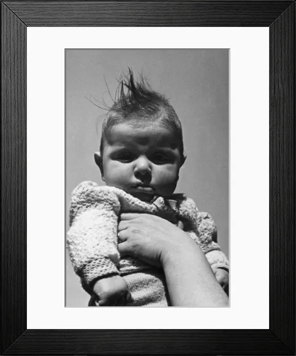 Framed Print : Baby in knitted jacket held up Framed Print : Baby in knitted jacket held up