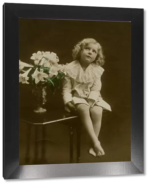 Young girl sitting on table with vase of flowers