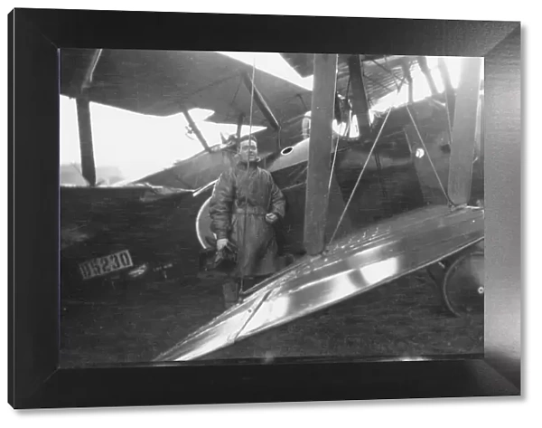 Pilot standing with biplane on an airfield, WW1