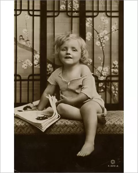 Little girl sitting on a bench with picture book