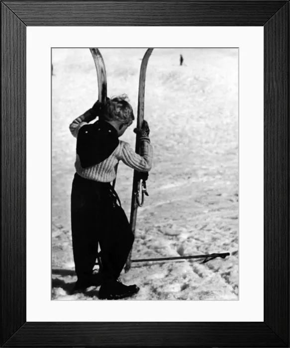 Framed Print : BOY SKIER. A little boy holding up a large pair of skis. Date: 1930s Framed Print : BOY SKIER. A little boy holding up a large pair of skis. Date: 1930s