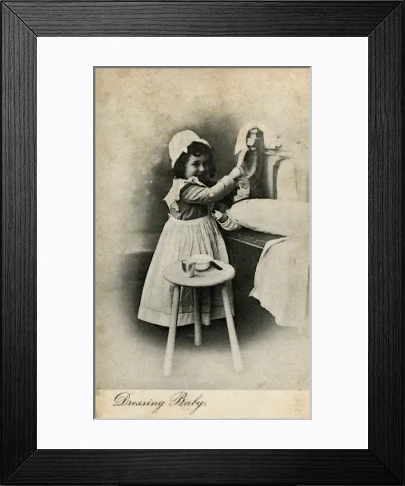 Framed Print : Dressing Baby -- little girl with her doll Framed Print : Dressing Baby -- little girl with her doll