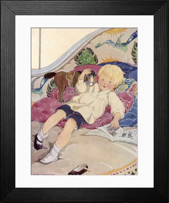 Framed Print : A boy lying on a bed with a book and a toy horse Framed Print : A boy lying on a bed with a book and a toy horse