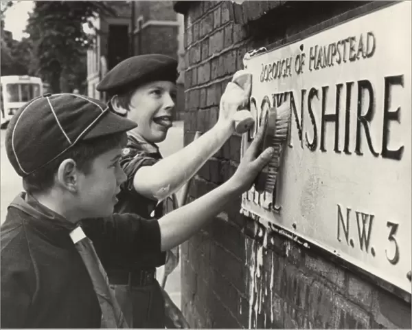 Boy Scouts cleaning street sign, London