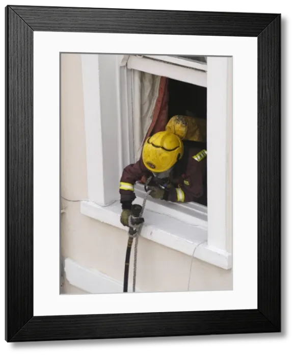 Framed Print : Firefighter using a rope to pull a hose up a building Framed Print : Firefighter using a rope to pull a hose up a building