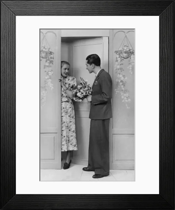 Framed Print : Woman greets her sweetheart who stands at door with flowers Framed Print : Woman greets her sweetheart who stands at door with flowers