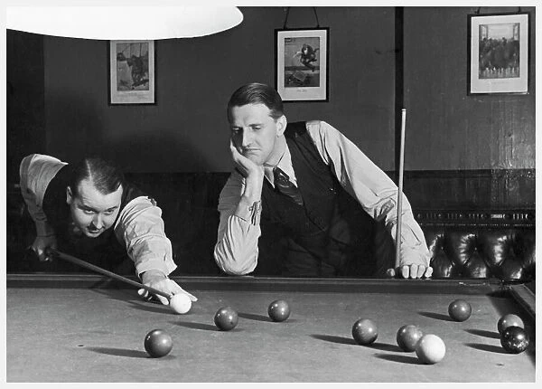 1930S Snooker Game. A snooker player prepares to play a shot as his partner looks on