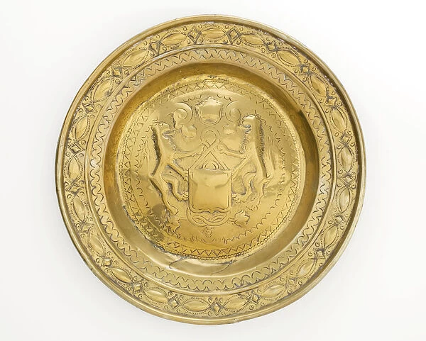 Almsdish in brass with a central hammered design featuring two lions flanking a shield