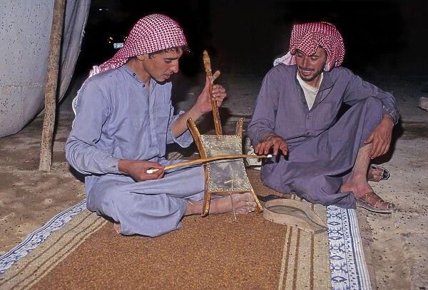 Bedouin men in tent in Syrian desert, one plays a rababah