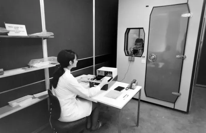 Framed Print : Biomedical centre, London -- a woman operates a machine while a patient in a locked room