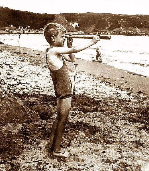 Boy on a beach with a telescope