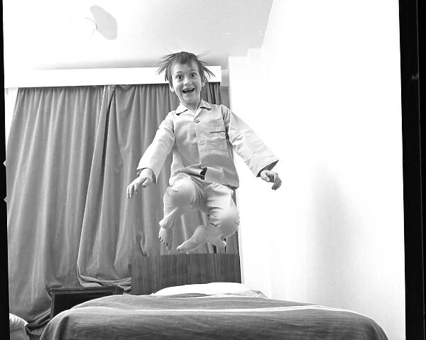 Boy bouncing up and down on a bed