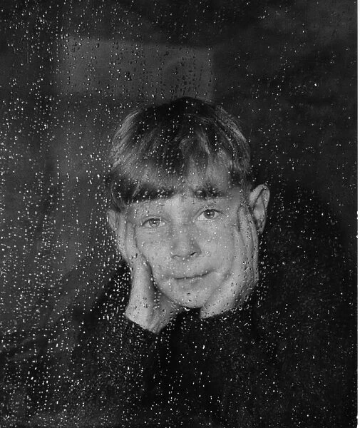 Boy looking through a window on a rainy day