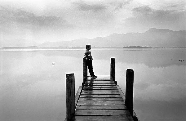 A boy looks out across Forggensee, near Fussen, Bavaria