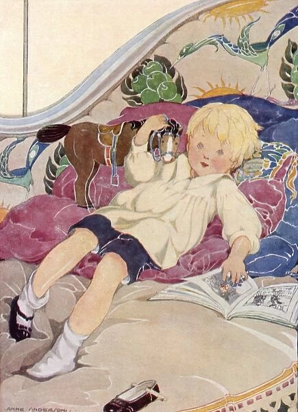 A boy lying on a bed with a book and a toy horse
