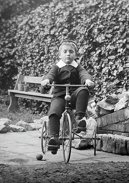 Boy playing on tricycle, early 1900s