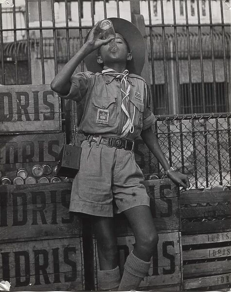 Boy scout drinking from a bottle of Idris, Mauritius