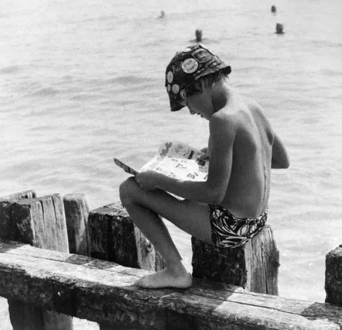 Framed Print : Boy sitting on breakwater reading a comic Framed Print : Boy sitting on breakwater reading a comic