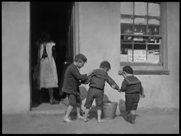 Three boys with a metal pail outside a shop