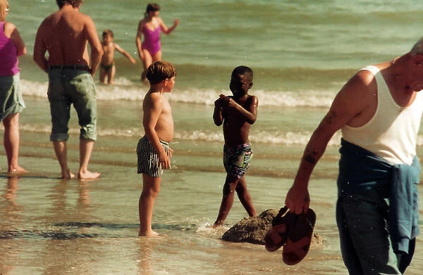 British Caribbean boy and English boy on the beach in Bright