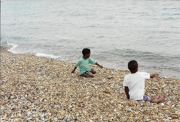 Two British Caribbean boys playing with stones on Brighton