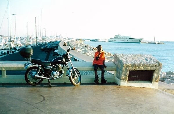 British Caribbean Heritage - Boy sitting by a motor bike in